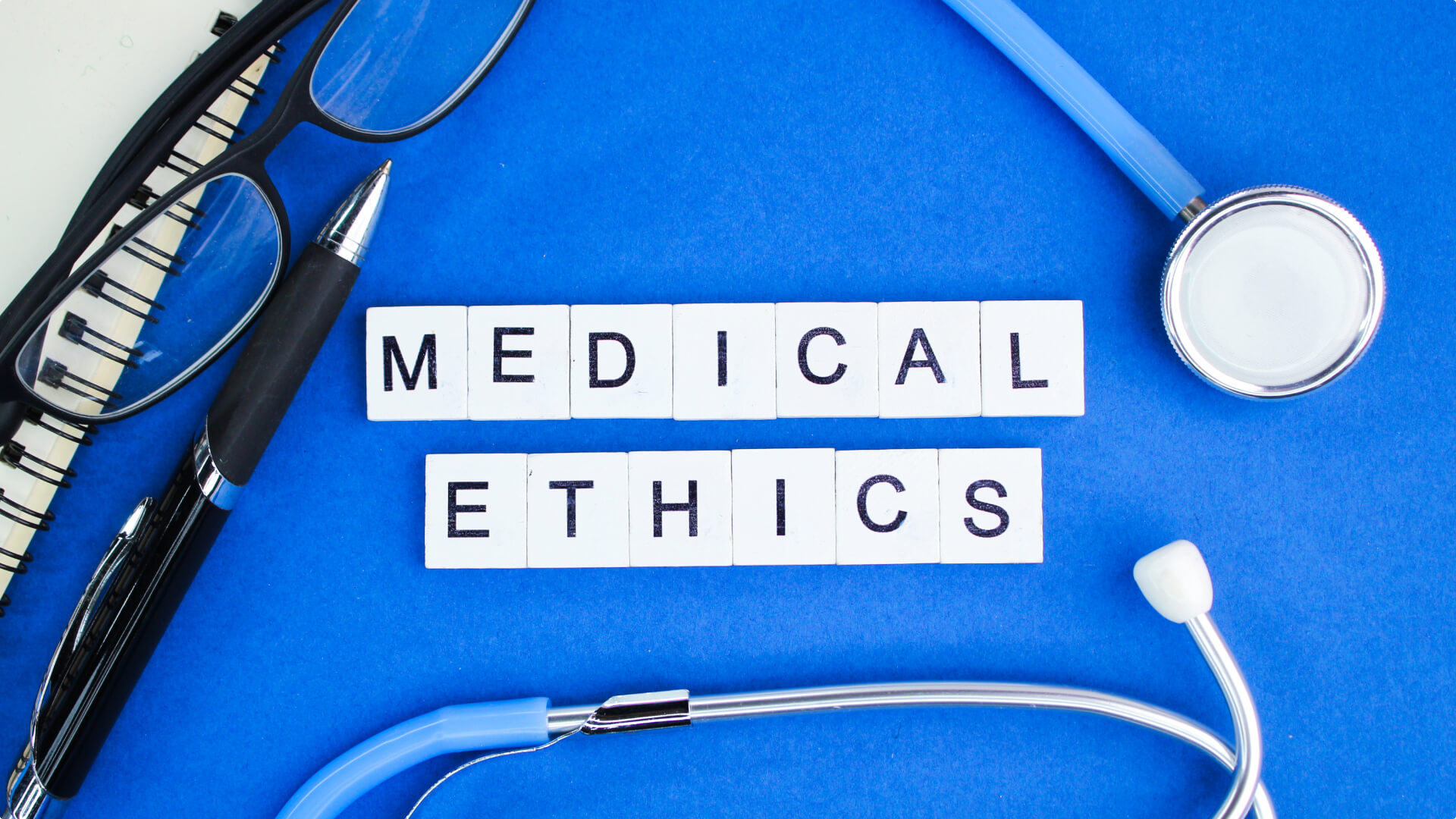 medical ethics on blue background with stethoscope, glasses and stethoscope
