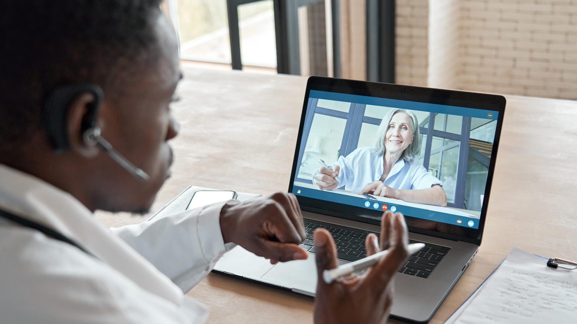 a doctor on a laptop talking to a patient on a video call
