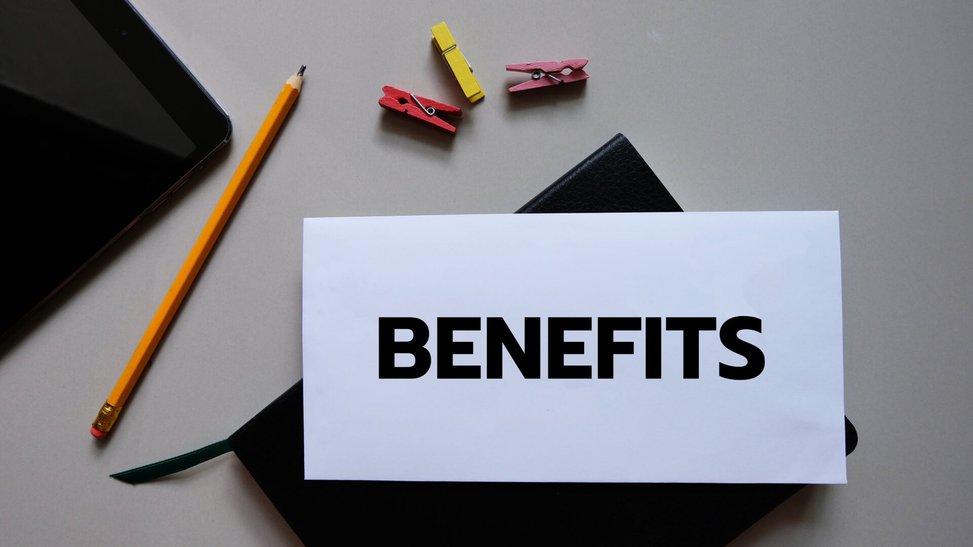 The word 'BENEFITS' prominently displayed on a piece of paper, symbolizing the advantages of using electronic medical records. Surrounding items like a digital tablet and notebook subtly underscore the integration of technology in managing health records efficiently.