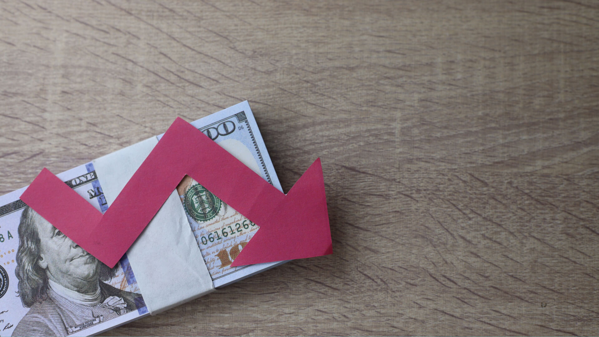 a red arrow pointing down on a stack of money