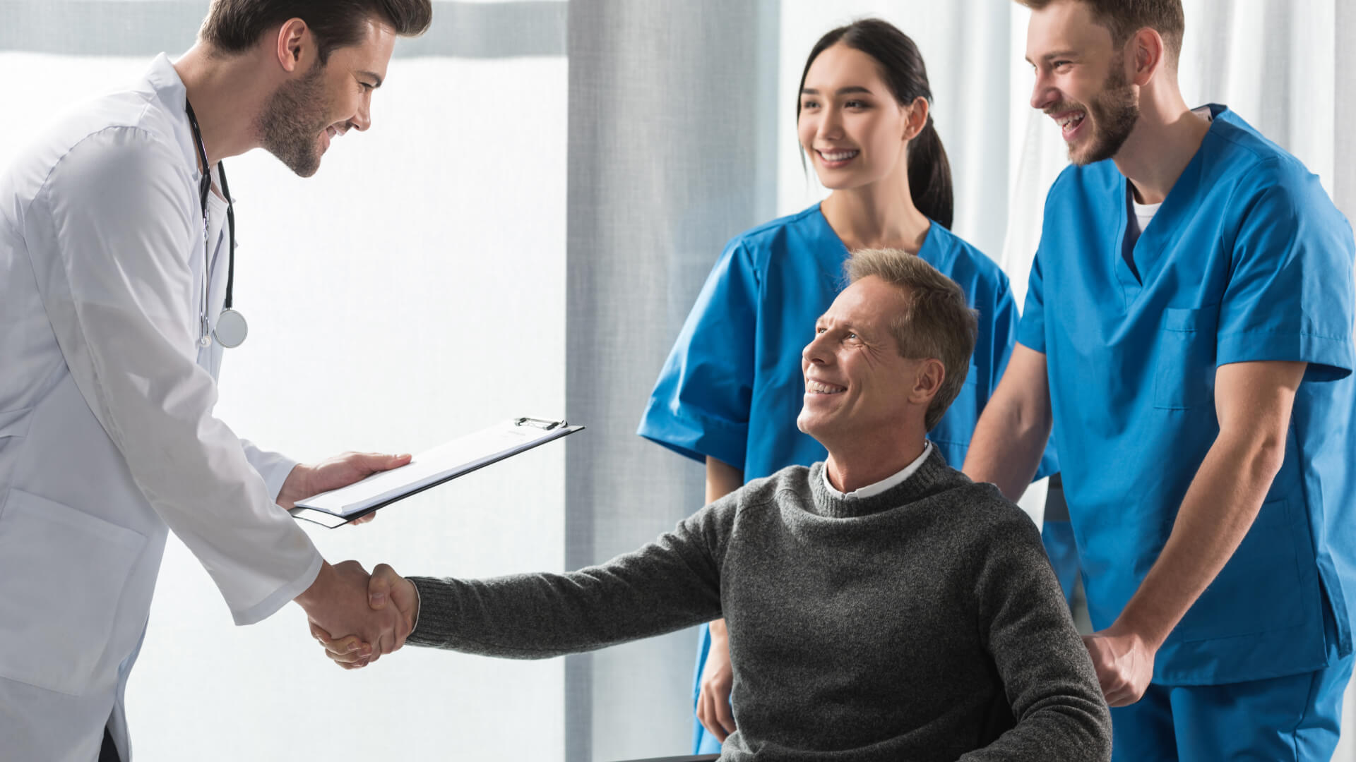 a group of doctors shaking hands with a patient in a wheelchair