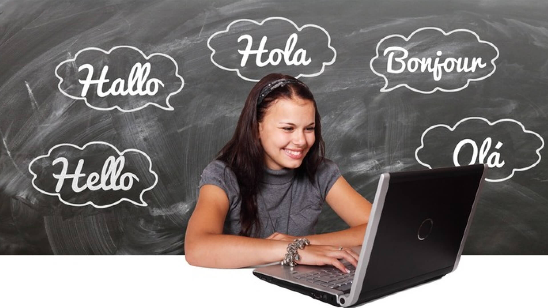 a girl is sitting in front of a laptop with hello written in different languages in the background