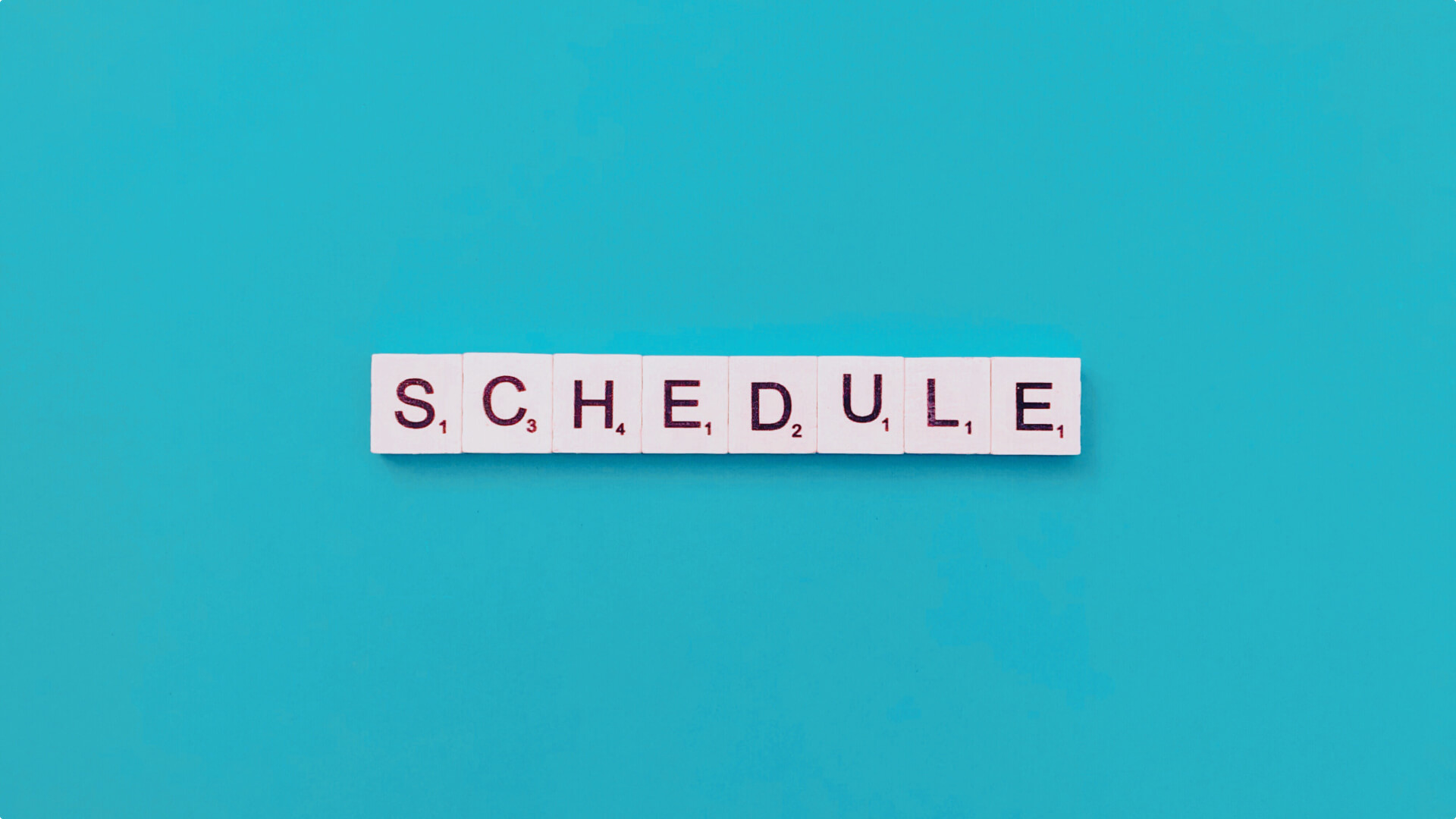 The word 'SCHEDULE' spelled out with letter tiles against a blue background.