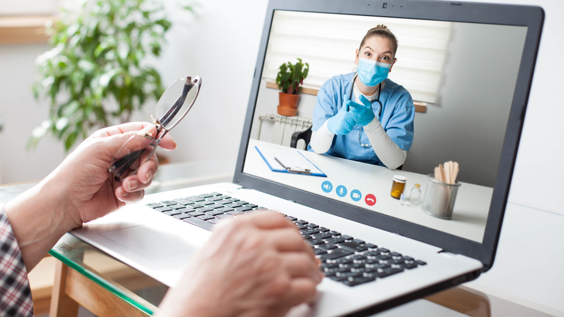 Person having a video call with a medical professional, who is giving instructions or advice, as indicated by her gestures.