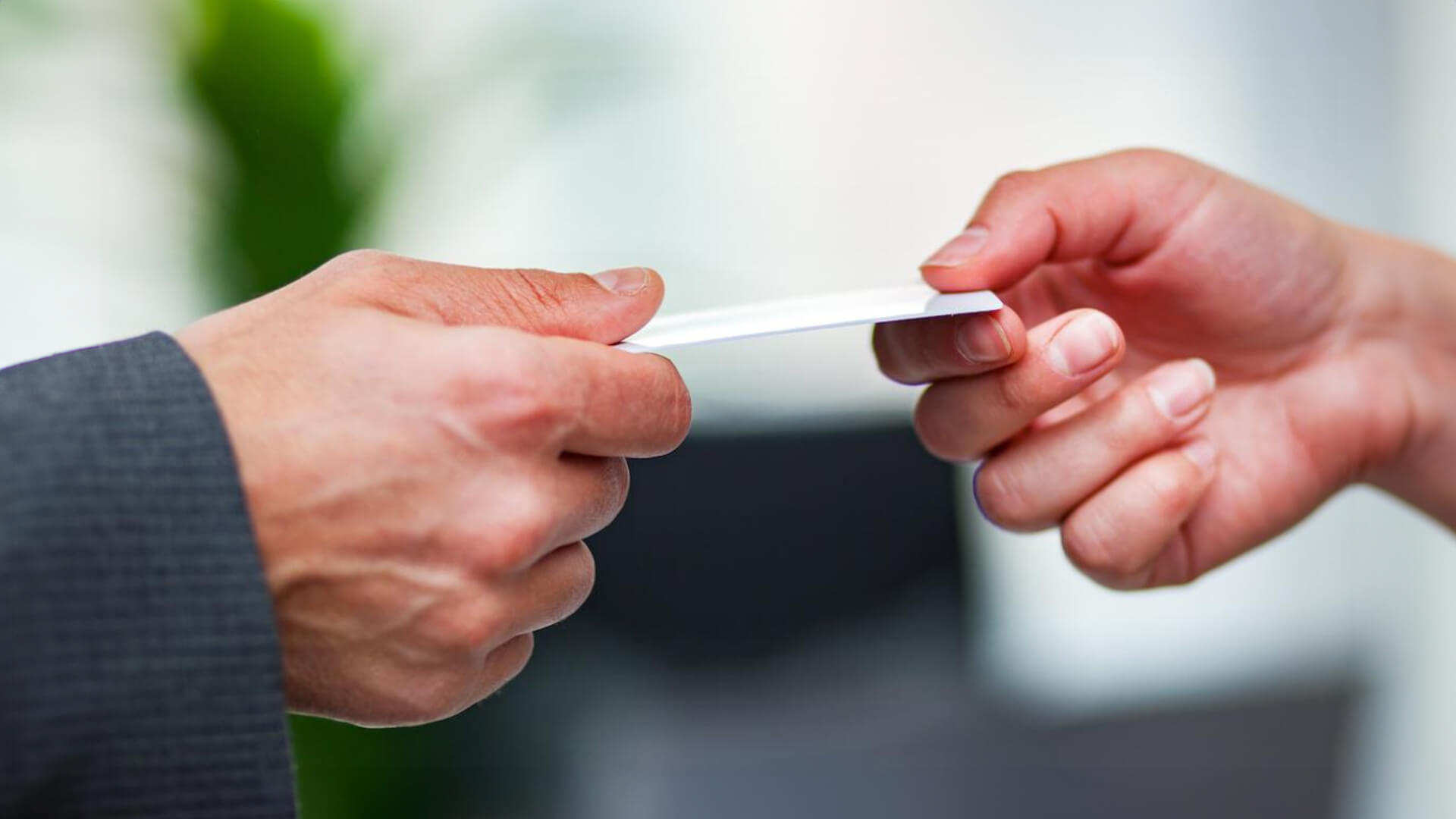 a professional handing a business card to another person