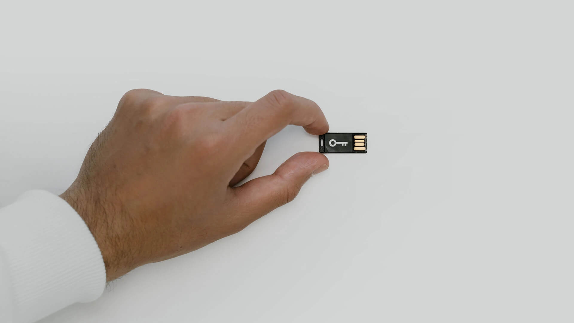 a person's hand holding a small micro sd card with a key symbol on it