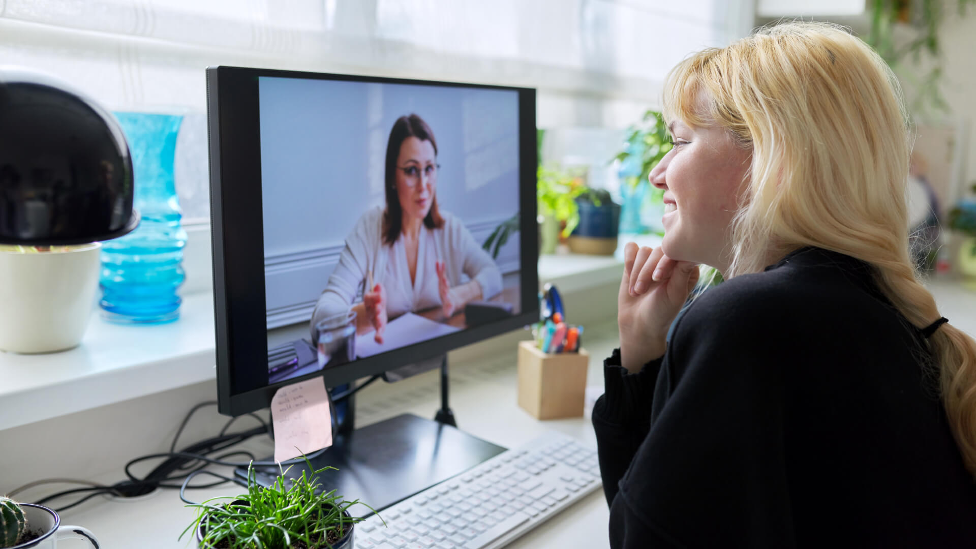 a woman talking to a therapist on a video call on her computer screen