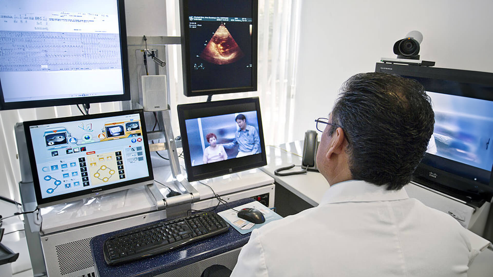 a doctor in a white coat looking at several monitors